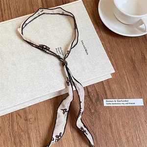 Dettaglio di collana in tessuto vintage con fiocchi neri e perla in legno regolabile