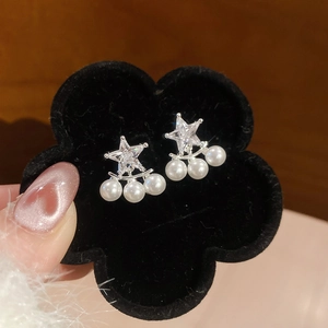 Primo piano di orecchini a stella in argento con zirconi e perle bianche pendenti