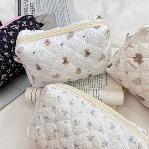 Gesteppte Kosmetiktaschen mit Blumenmuster und Bärenprint auf weißem Hintergrund