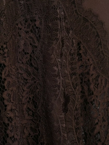 Macro detail of dark brown lace fabric with intricate floral patterns and eyelash trim