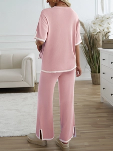 Detail of pink knit lounge set featuring white contrast trim and stylish side-slit leg cuffs