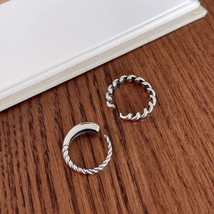 Detailed macro view of 925 sterling silver twist ring and smooth band on wood