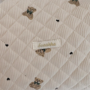 Detail of quilted corduroy pouch with vintage bear pattern and brand label
