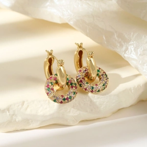 Elegant gold hoop earrings featuring multi-color zircon stones on white rock display