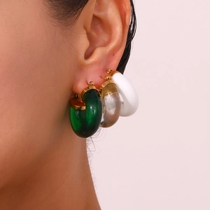 Close-up of model wearing C-shaped acrylic hoop earrings in green, clear, and white