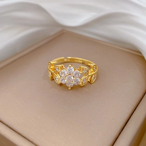 Detail shot of a gold flower ring with sparkling zircon stones on a silk fabric background