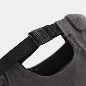 Detail of adjustable black plastic buckle strap on distressed cotton brimless cap