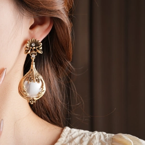 Détails de boucles d'oreilles vintage avec fleurs ciselées, cristaux et perle blanche