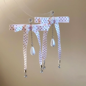 Close-up of pink polka dot ribbon bow earrings with pearl tassels and crystal accents