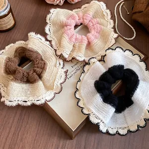 Three-piece large knitted scrunchies with elegant lace trim displayed on a wooden tray