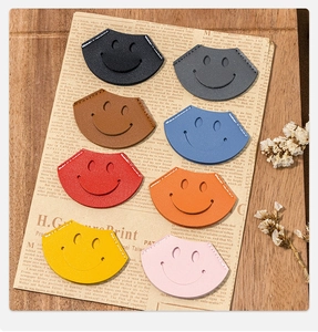 Detail of 8 colorful leather smiley face cord organizers on a vintage paper backdrop