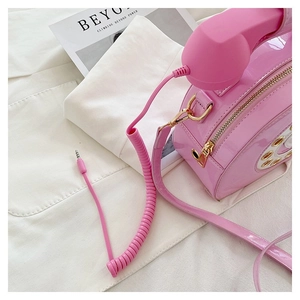 Macro detail of pink retro telephone bag featuring a spiral cord and gold hardware