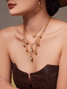 Detail of gold multilayered necklace with heart, butterfly and star pendants on a model