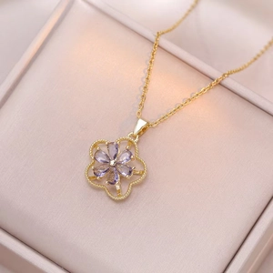 Close-up of golden spinning flower necklace with light purple stones on pink silk