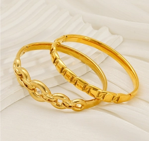 Close-up of gold-plated stainless steel bangles with chunky chain and geometric textures