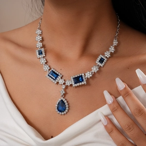 Dettaglio della collana argentata con gemme blu a goccia e quadrate per uno stile elegante