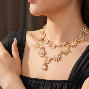 Détail d'un collier vintage doré à plusieurs rangs avec papillon en strass et cristal goutte
