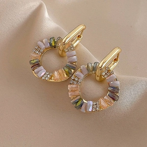 Detail of vintage gold hoops with colorful zircon stones on beige silk fabric