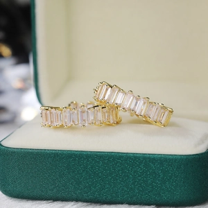 Detail showing luxurious gold rectangular cubic zirconia hoop earrings in a green box