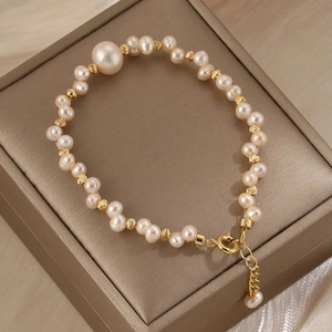 Dettaglio del bracciale di perle intrecciate con distanziatori dorati e chiusura a moschettone