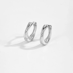 Macro shot of silver hoop earrings with embedded zircon accents on a white surface