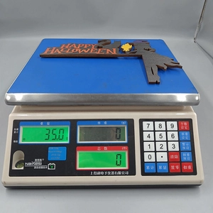 Detail view of a 35g Halloween wooden door corner sign on a digital weight scale