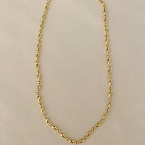 Minimalist 925 sterling silver beaded necklace in golden finish on textured background