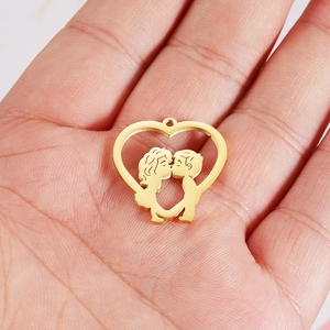 Gold stainless steel hollow heart pendant with kissing couple detail held on palm