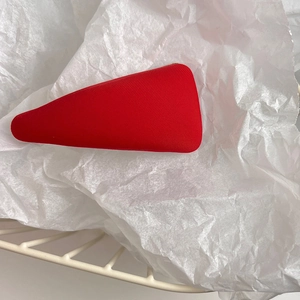 Detail shot of a red triangular sponge hair clip on textured white tissue paper