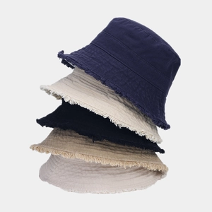 Detailed stack of cotton bucket hats showing frayed edges in various neutral colors