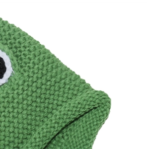 Close-up of green knitted frog hat featuring thick wool texture and cartoon eyes