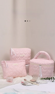 Three-piece pink heart-quilted makeup bag set featuring elegant LOVE IS ETERNAL ribbon detail