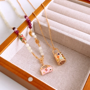 Détail de colliers de style français en perles et or avec pendentifs colorés en émail