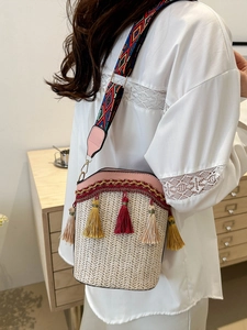 Detail of woven bucket bag featuring colorful tassels and embroidered geometric strap