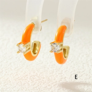 Detail of C-shaped orange enamel earrings with a sparkling round zircon stone inlay