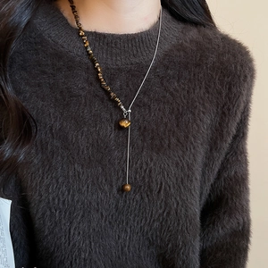 Close-up of model wearing a tiger eye stone Y-shaped necklace with silver beads
