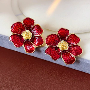 Primer plano detallado de pendientes vintage de flores rojas con centro de rosas doradas