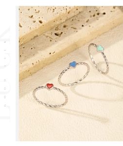 Detailed view of colorful enamel heart rings with polished twisted rope metal bands