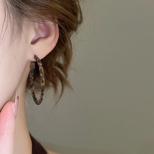 Boucles d'oreilles créoles en résine à motif léopard portées par un mannequin