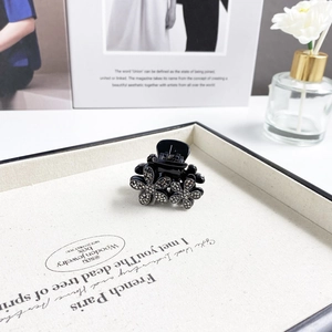 Elegant black flower claw clip with rhinestones displayed on a cream jewelry tray