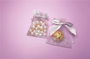 Macro shot of purple mesh drawstring gift bags with elegant ribbon bows for jewelry storage