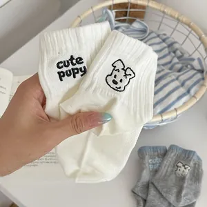 Close-up of cute puppy embroidery on soft white and gray cotton knitted ankle socks