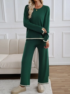 Detail view of dark green knit set with cream trim on sleeves and wide-leg trousers