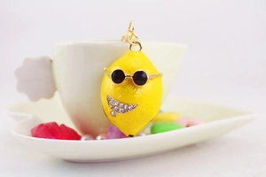 Dettaglio macro portachiavi a limone giallo con occhiali da sole e sorriso in strass