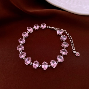 Macro detail of luxury silver bracelet featuring oval pink zircon stones on velvet