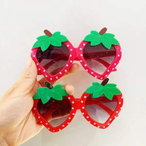 Detail of red strawberry-shaped children's sunglasses with white dots and green leaves