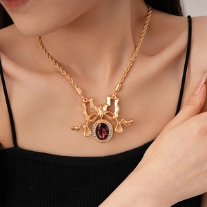 Detail of vintage gold bow necklace with purple gemstone and crystals on model