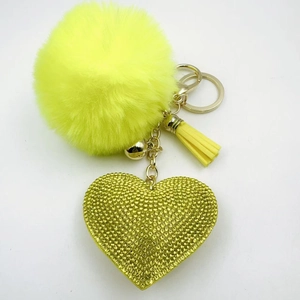 Close-up of yellow rhinestone heart pendant with fluffy pompom and gold keychain