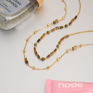 Detailed view of gold plated chain with multi-shape tiger eye beads in a layered style