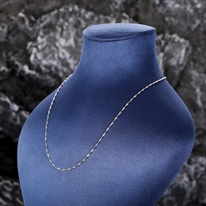 Close-up of a shiny silver twist chain necklace displayed on a blue velvet neck model